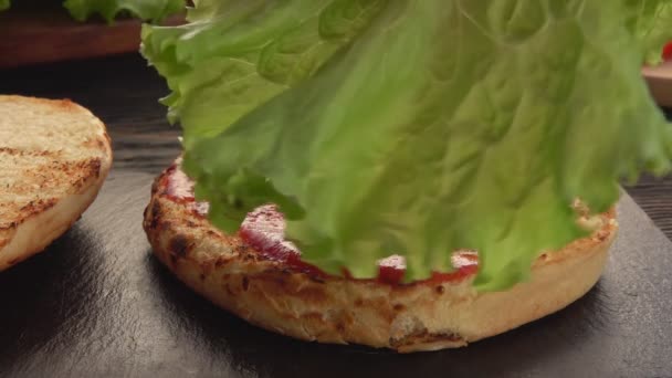 Sallad placeras ovanpå den färska hemlagade grillade burgaren — Stockvideo