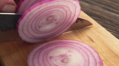 Ahşap tahtada soğan halkalarını kesen ellerin yakın çekimi