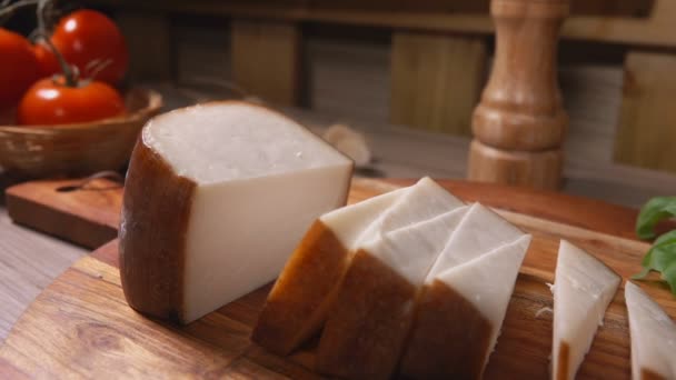 Κοντινό πλάνο ενός πιρουνιού που παίρνει ένα κομμάτι ημίσκληρου τυριού από την ξύλινη σανίδα — Αρχείο Βίντεο