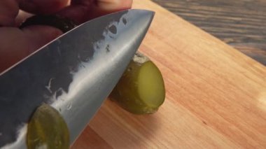 Salatalıklar, ev yapımı ızgara burger için tahtanın üzerinde bir bıçakla kesilir.