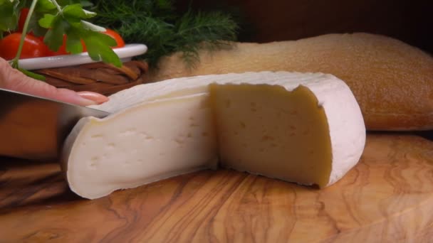 Jemný krémový francouzský sýr krájený nožem na dřevěné desce — Stock video
