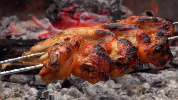 Νόστιμα φτερά κοτόπουλου στα σουβλάκια τηγανίζονται πάνω από την ανοιχτή φωτιά με γοργούς ρυθμούς. — Αρχείο Βίντεο