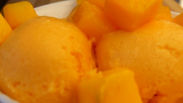 I cubetti di mango fresco cadono nella ciotola piena di gelato al mango surgelato — Video Stock