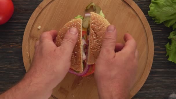 Top view of the male hands opening fresh homemade burger cut in two halves — Stock Video