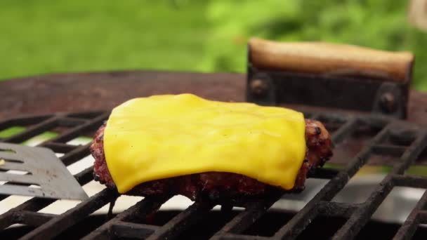 Close-up van de zelfgemaakte hamburgerkotelet met gesmolten kaas bovenop op een grill — Stockvideo