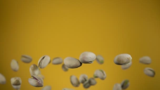 Close-up of salted pistachios flying up on a yellow background — Vídeo de Stock