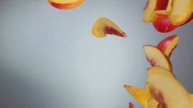 Taze sulu şeftali dilimleri düşüyor ve beyaz arka planda dönüyor.