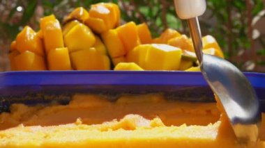 Kaşık yavaşça donmuş mango dondurmalı dondurmayı kaşıklıyor.