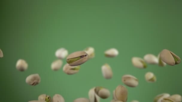 Close-up of salted pistachios flying up on an olive green background — Stock Video