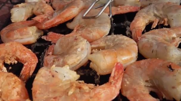 Gros plan de grosses crevettes grillées tournantes avec pinces de cuisine sur la grille de cuisson — Video