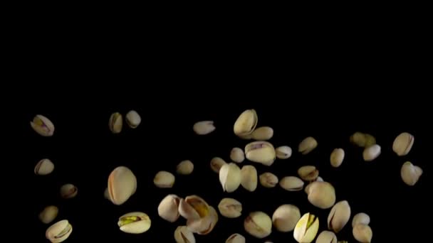 Gesalzene Pistazien fliegen vor schwarzem Hintergrund auf — Stockvideo