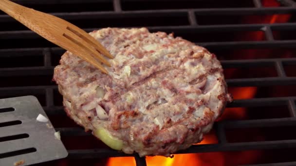 Close-up of the appetizing homemade burger cutlet flipped above the open fire — Stok Video