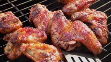 Izgarada kızartılmış ve döndürülmüş lezzetli tavuk kanatlarının yakın çekimi. 