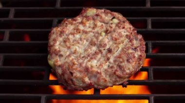 Et ve soğandan yapılmış hamburgerin yakın çekimi ateşin üstünde kızarıyor.