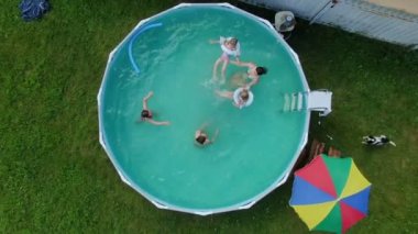Arka bahçedeki yuvarlak yüzme havuzunda yüzen çocukların hava çekimi