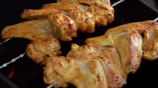 Κοντινό πλάνο με μαριναρισμένες φτερούγες κοτόπουλου στα σουβλάκια που τηγανίζονται πάνω από φωτιά σε εξωτερικούς χώρους — Αρχείο Βίντεο