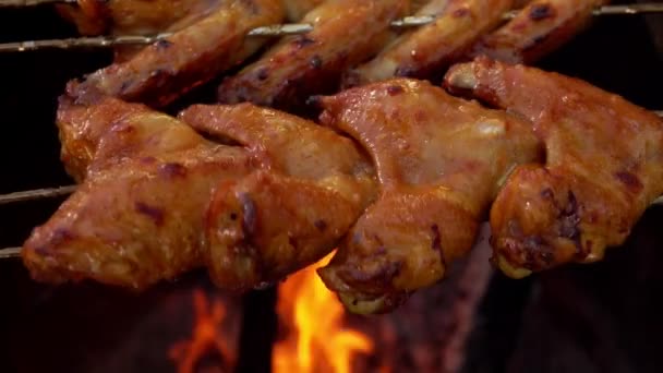 Κοντινό πλάνο των νόστιμων φτερούγων κοτόπουλου στα σουβλάκια περιστρέφεται πάνω από την ανοιχτή φωτιά — Αρχείο Βίντεο