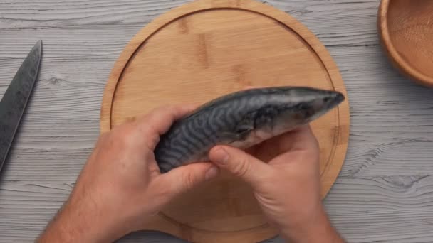 Blick von oben auf die Männerhände, die beginnen, die Fische auf dem runden Holzbrett zu säubern — Stockvideo