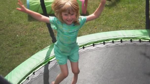 Ένα χαρούμενο ξανθό κορίτσι πηδάει στο τραμπολίνο στην πίσω αυλή. — Αρχείο Βίντεο
