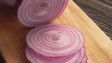 Ahşap tahtada kırmızı soğan halkalarını kesen ellerin yakın çekimi