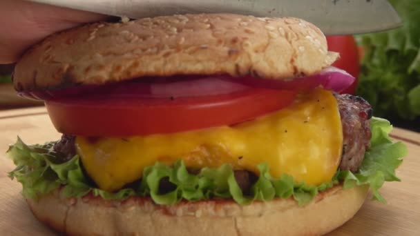 Super close-up de um hambúrguer grelhado caseiro fresco cortado com uma faca em duas metades — Vídeo de Stock