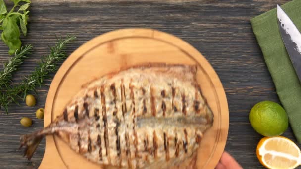 Händerna placerar en träskiva med en läcker grillad vit makrill fisk — Stockvideo