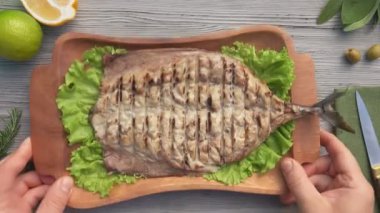 Eller lezzetli ızgara uskumru balığıyla ahşap bir tabak yerleştiriyor.