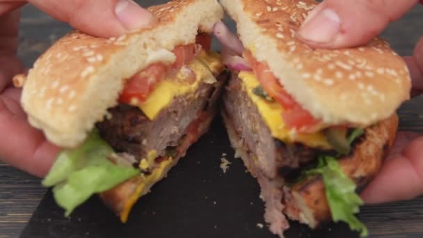 Las manos masculinas están abriendo hamburguesa a la parrilla fresca con chuleta de carne cortada en dos mitades — Vídeos de Stock