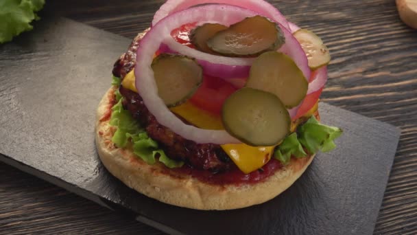 Izgara susamlı ekmeğin üst görüntüsü taze ev yapımı ızgara burgerin üzerine konur. — Stok video