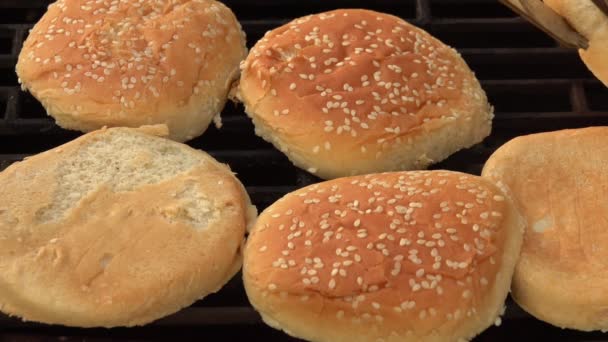 Gros plan sur les pains de hamburger au sésame retournés sur la grille du gril — Video