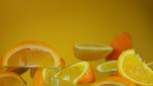 Сочные сладкие ломтики апельсина летят на желтом фоне — стоковое видео