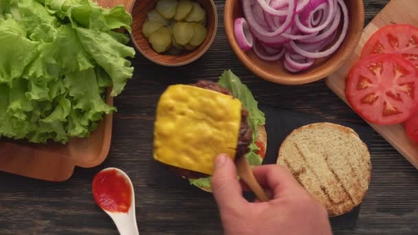 Grilled vlees cutlet met kaas wordt geplaatst op de top van een verse zelfgemaakte burger — Stockvideo