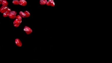 Nar tanecikleri yavaş çekimde siyah arkaplana çapraz düşüyor.