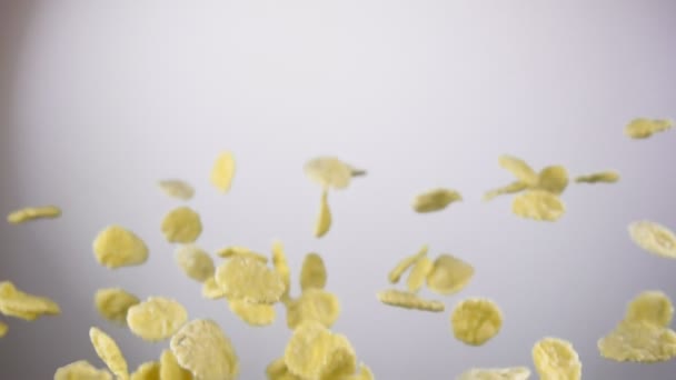 Los copos de maíz de cereales están rebotando y girando sobre el fondo blanco — Vídeos de Stock