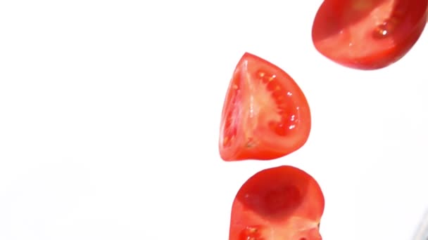 Gros plan des moitiés de tomates fraîches tombant en diagonale sur un fond blanc — Video