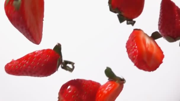 Close-up van de rode rijpe aardbeien helften vliegen op een witte achtergrond — Stockvideo