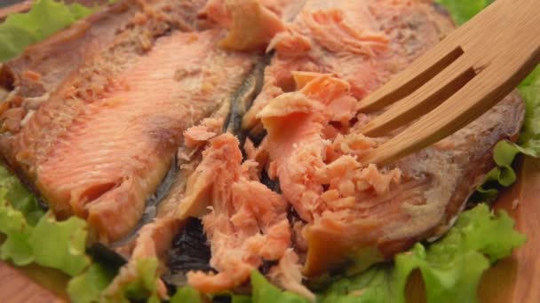 Close-up dari garpu kayu mengambil sepotong ikan bakar merah dari piring — Stok Video