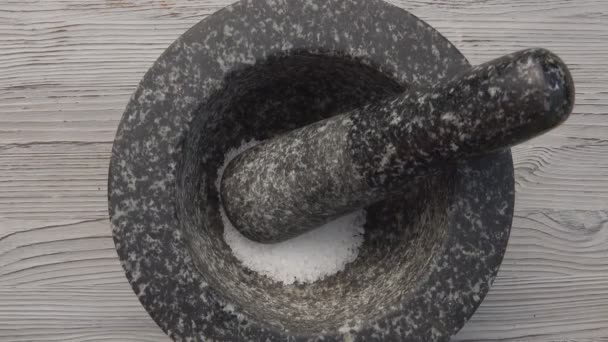 Vedere de sus a mâinilor care pun sare și zahăr brun în mortarul de piatră gri — Videoclip de stoc