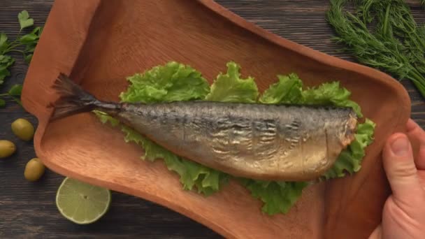 Top view of the hand putting a wooden plate with a juicy grilled red char fish — Stock Video
