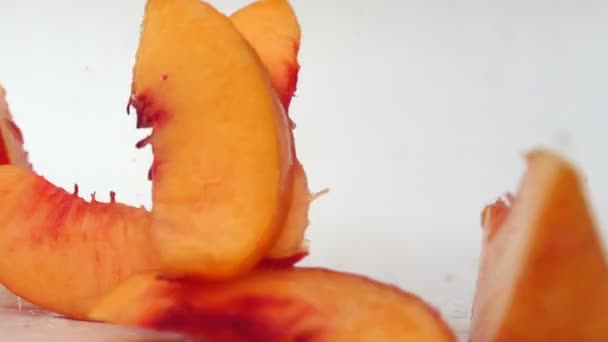 Pfirsichscheiben fallen auf eine nasse Oberfläche — Stockvideo