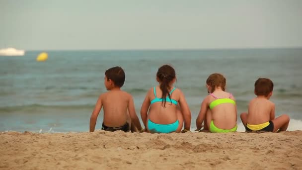 Děti sedí na pláži