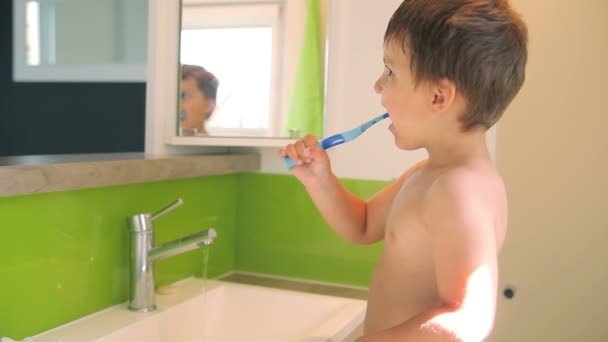 The little boy brush his teeth in the mirror — стоковое видео