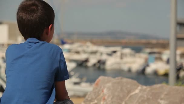 Garçon regarde un yacht sur la mer — Video