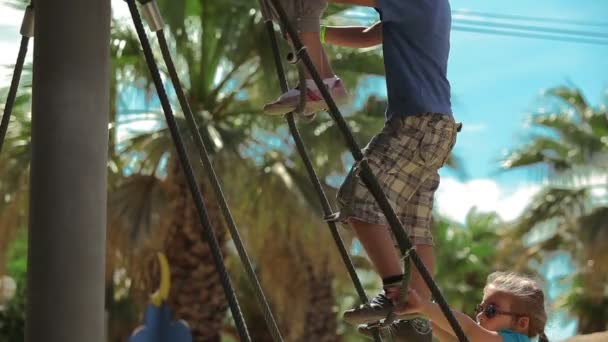 Barn klättra upp en repstege på lekplatsen — Stockvideo