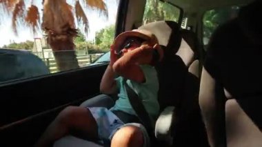 Çocuk arabada rides. Çocuk güneş gözlüğü takıyor