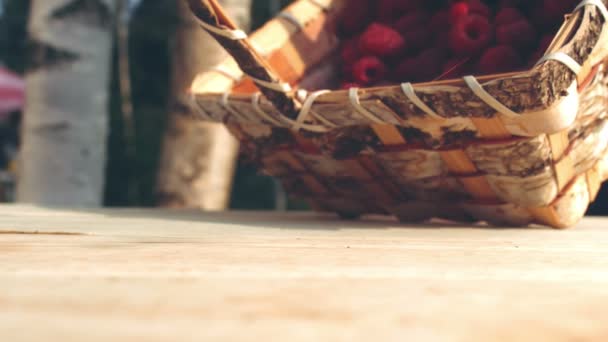 Panier de framboises mûres versé sur une table en bois 