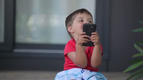 Menino jogando em um telefone celular — Vídeo de Stock