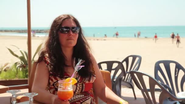 Young woman drinking a cocktail on the beach — Stock Video