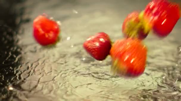 Wet strawberry falls on the surface with a splash — Stock Video