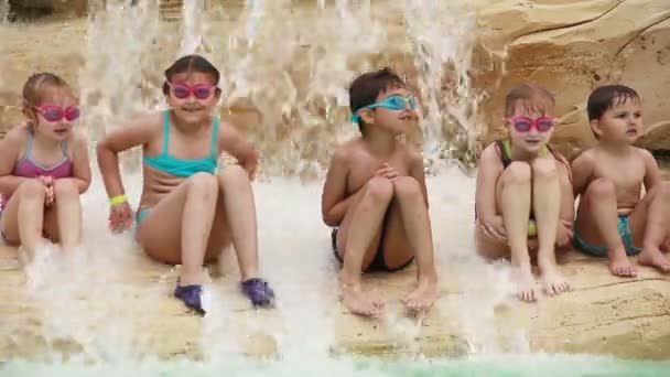 Niños mojados se sientan en una roca cerca del agua — Vídeos de Stock